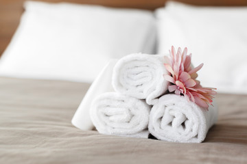 towels and flower on bed in hotel room