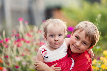 Fototapeta na wymiar Portrait of happy cheerful brother and sister in summer garden,