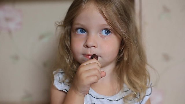 a little two-year-old girl paints her lips with her mother's lipstick.