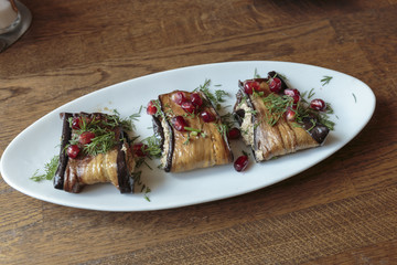 Eggplant rolls, stuffed with nuts and cheese, decorated by pomegranate seeds. Vegan food.