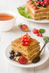 Honey cake with strawberries, mint and currant, a Cup of tea on a light background.