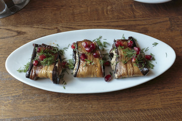 Eggplant rolls, stuffed with nuts and cheese, decorated by pomegranate seeds. Vegan food.