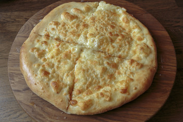 Fresh cheese pizza on a wooden plate on the table, Italian traditional appetizer, high angle view.