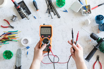 Top view of different electrical tools on white concrete background, flat lay. Tools for an...