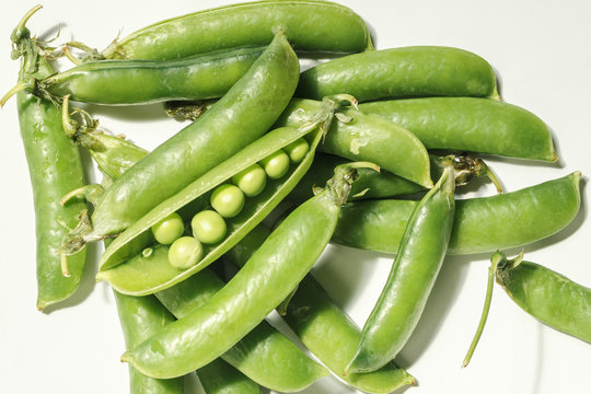 pods of green peas with closed and opened flaps and peas