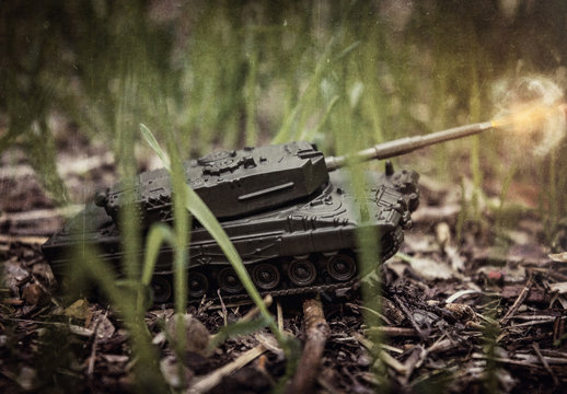 Toy tank on nature background with ground and green grass