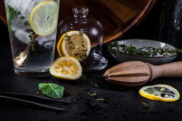 A glass of lemonade and ingredients for it on a dark background with wet glass