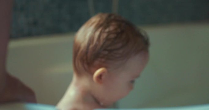 Mother washing baby boy in a bathtub. shot in slow motion