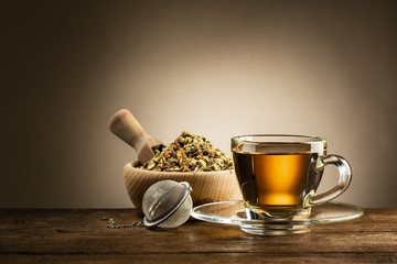 glazen kopje thee met zetgroep en kruidenthee op houten tafel