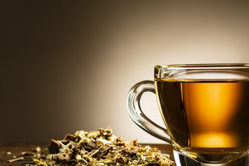 closeup of glass cup of tea with herbal on wooden table
