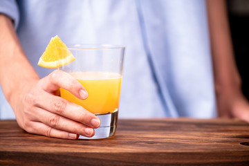 Woman holding a fresh orange juice in a glass.