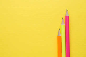 Obraz premium Bright colored pencils on yellow background. Copy space