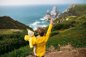 Woman with young child is delighted of the ocean near the cape of rock in Portugal