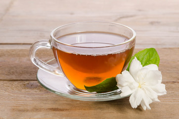 Glass cup of Tea with jasmine flowers on wooden table