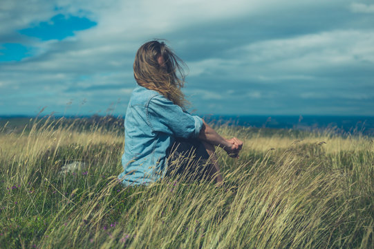 Young woman sitting in field on windy day