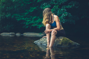 Fototapeta premium Woman relaxing on rock in river