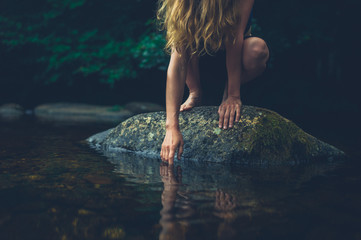 Young woman sitting on rock in a river - 215638868