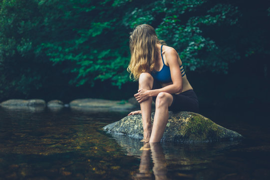 Woman relaxing on rock in river