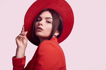 Elegant beautiful woman in a red fashionable suit and wide hat