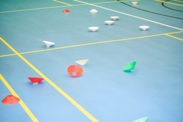 Different coloured cones on the floor of a gym