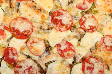 Surface of baked pizza close-up. Tomatoes, cheese, zucchini, eggplants. Food concept