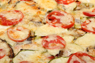 Surface of baked pizza close-up. Tomatoes, cheese, zucchini, eggplants. Food concept