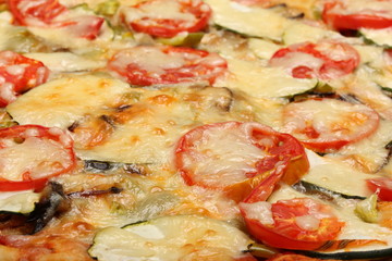 Surface of baked pizza close-up. Tomatoes, cheese, zucchini, eggplants. Food concept