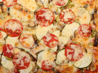 Surface of baked pizza close-up. Tomatoes, cheese, zucchini, eggplants. Food concept