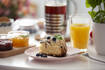 Close-up on cake on plate on a table with orange juice during breakfast. Real photo