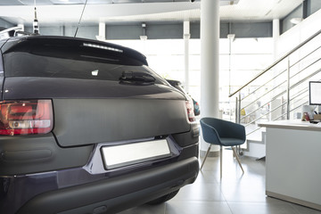 Close-up of black mat car in the foreground and office desk with chair in the background standing...