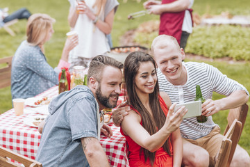 Smiling friends taking selfie during grill party in the garden