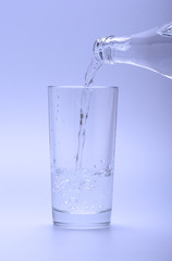 Mineral cold water pouring into glass from bottle