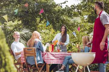 Low angle of man grilling food and happy friends during birthday party in the garden