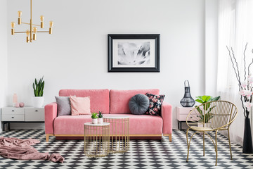 Real photo of a glamour living room interior with a powder pink sofa, checkered floor, painting and...