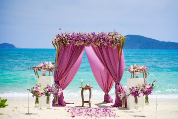 Arch for a wedding ceremony on the beach and a tropical beach. Fabrics, bamboo, decor of flowers, petals of color Fuchsia.