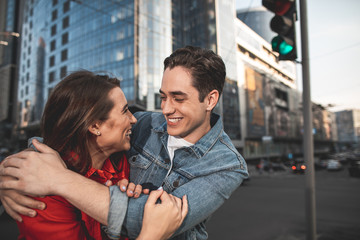 Side view of smiling couple embracing each other with love. They are looking with smile while sightseeing in city