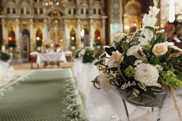 Beautiful fresh white flowers bouquet decoration for wedding ceremony in christian orthodox church, interior closeup