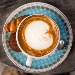 Classic foamy cappuccino Coffee Cup with crackers and spoon on a marble restaurant table
