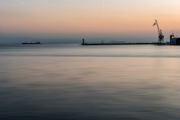 Thessaloniki Pier and Lighthouse at peaceful sunset, with a single ship in the background, Greece