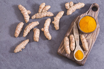 Turmeric powder and fresh turmeric on wooden background