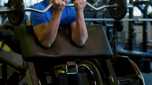 Tilt up of determined muscular man training in gym: he breathing hard and making bicep curls with barbell