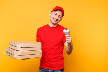 Delivery man in red cap t-shirt giving food order pizza boxes isolated on yellow background. Male employee pizzaman courier in uniform holding heart italian pizza in cardboard flatbox. Service concept