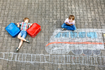 Two little kids boys having fun with train picture drawing with colorful chalks on ground © Irina Schmidt