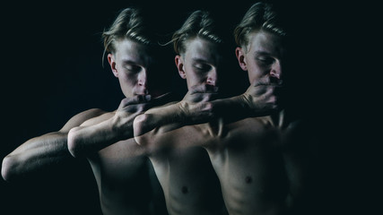be silent. Don't speak. Young beautiful naked guy covers mouth with his hands. Multiple exposure. Creative emotional man portrait. Dark background
