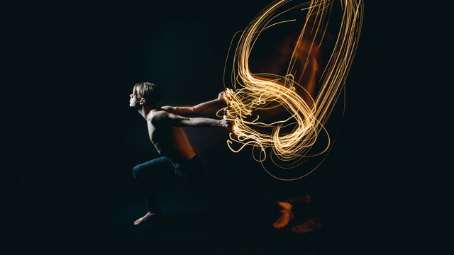 metaphor purposeful beautiful naked young man resistance to battle with problems and depression. Drawing with light. Long exposure creative emotional portrait. Dark background.