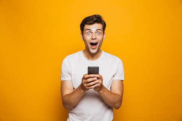 Portrait of a shocked young man holding mobile phone