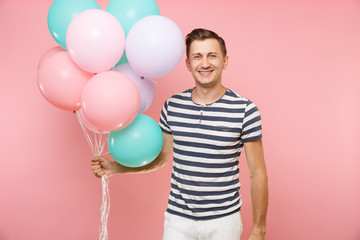 Fototapeta na wymiar Portrait of fascinating young happy man wearing striped t-shirt holding colorful air balloons isolated on bright trending pink background. People sincere emotions lifestyle concept. Advertising area.