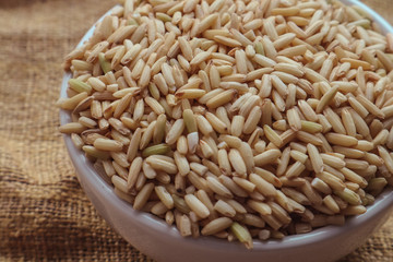 Raw brown rice in a bowl. top view food background