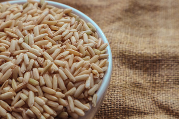 Raw brown rice in a bowl. top view food background