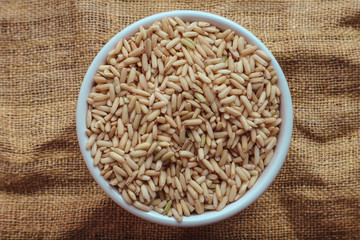 Raw brown rice in a bowl. top view food background